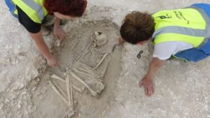 Archaeologist uncovering one of the burials (by BBC News)